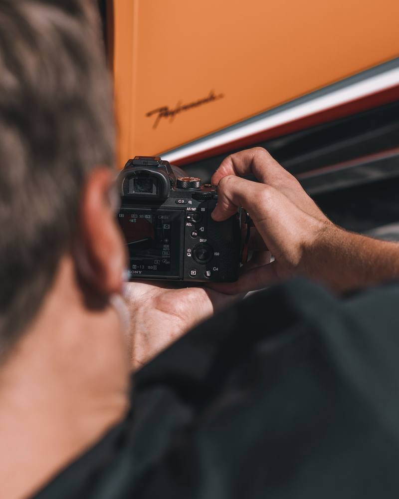 Sachverständiger fotografiert mit der Kamera ein Detail an einem Fahrzeug