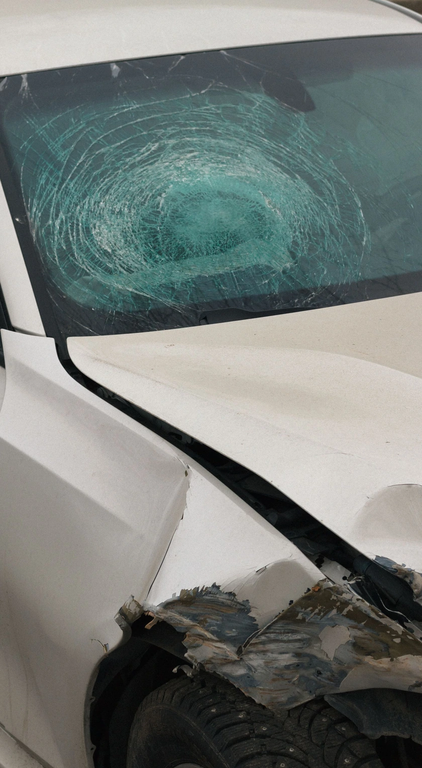 Weißes Unfallauto mit zersplitterter Windschutzscheibe und eingedrückter Front