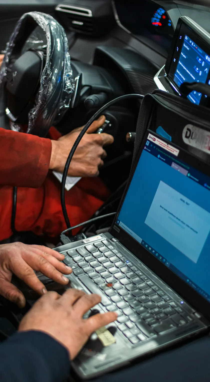 Laptop ist per Diagnosekabel im Fahrzeuginnenraum angeschlossen und liest die Steuergeräte aus