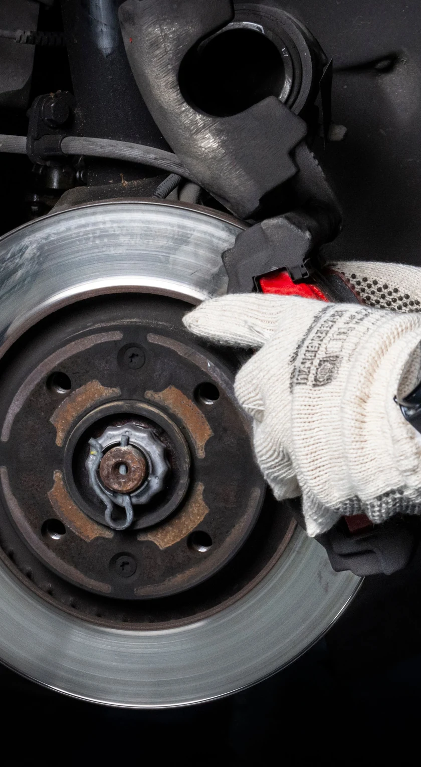 Behandschuhte Hand prüft die Bremsscheibe eines Fahrzeugs