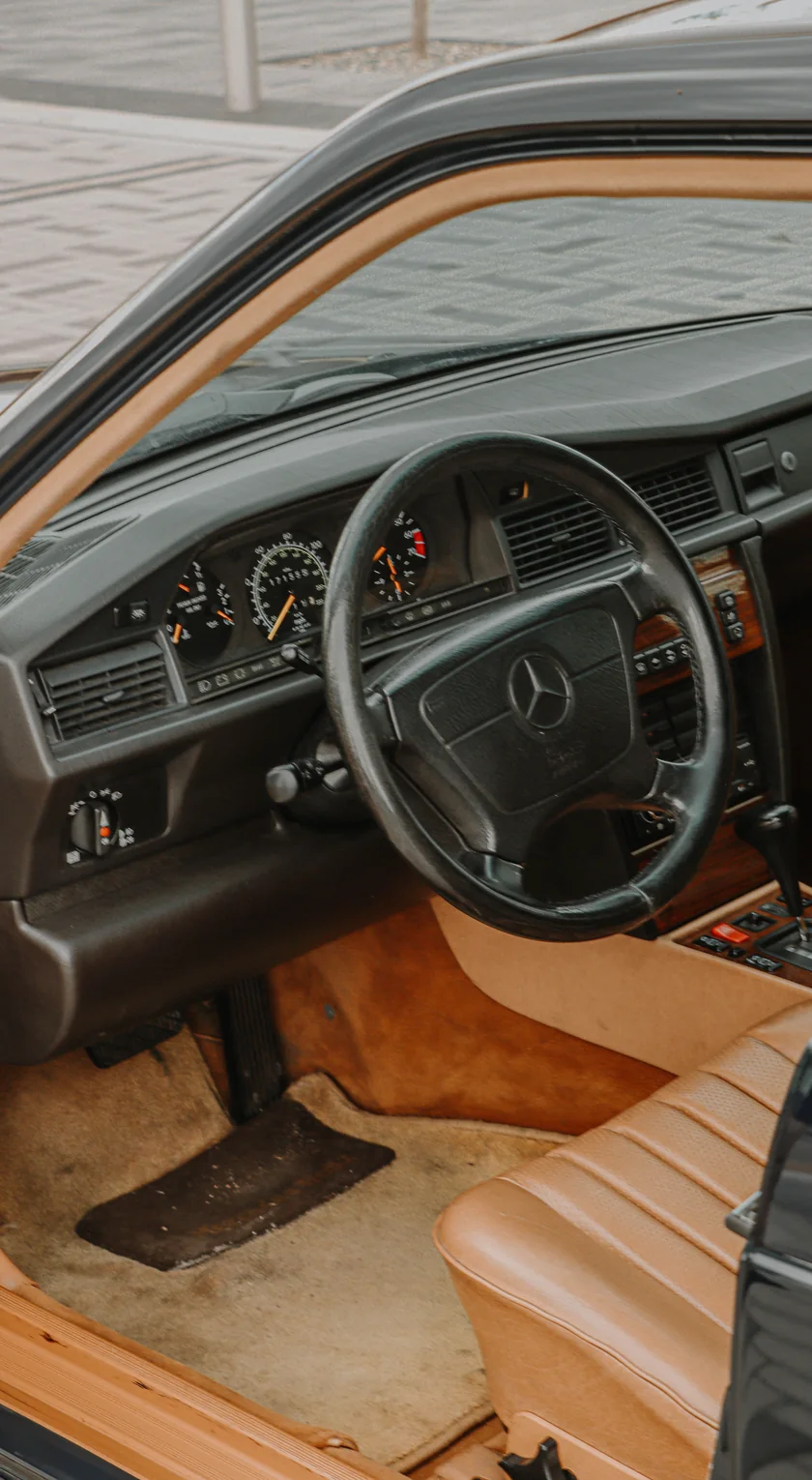 Gepflegter Innenraum eines Mercedes 190E mit Lederlenkrad und Tacho