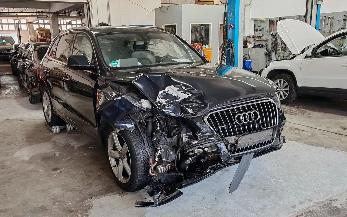 Dunkelblauer Audi Q5 mit zerstörter Front in einer Werkstatt