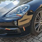 Schwarzer Porsche Panamera mit Frontschaden, die beschädigten Stellen sind mit Markierungspfeilen des Sachverständigen gekennzeichnet