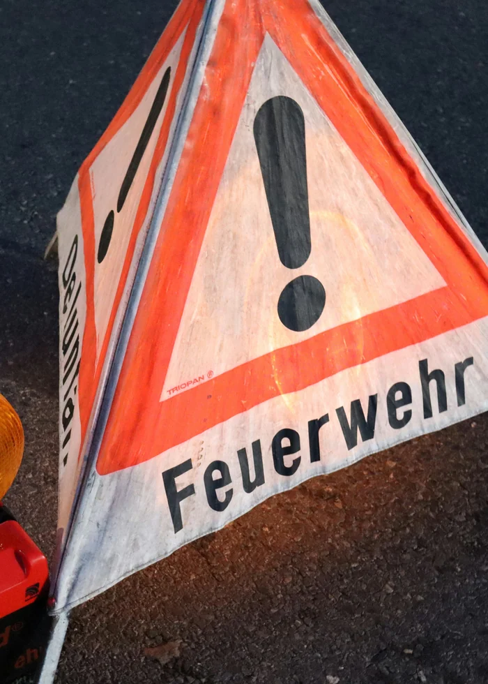 Warndreieck der Feuerwehr mit gelber Warnleuchte auf der Fahrbahn