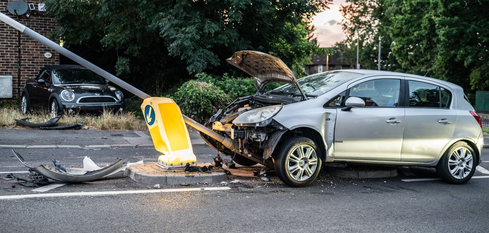 Silberner Kleinwagen mit eingedrückter Front nach dem Aufprall auf einen Laternenmast