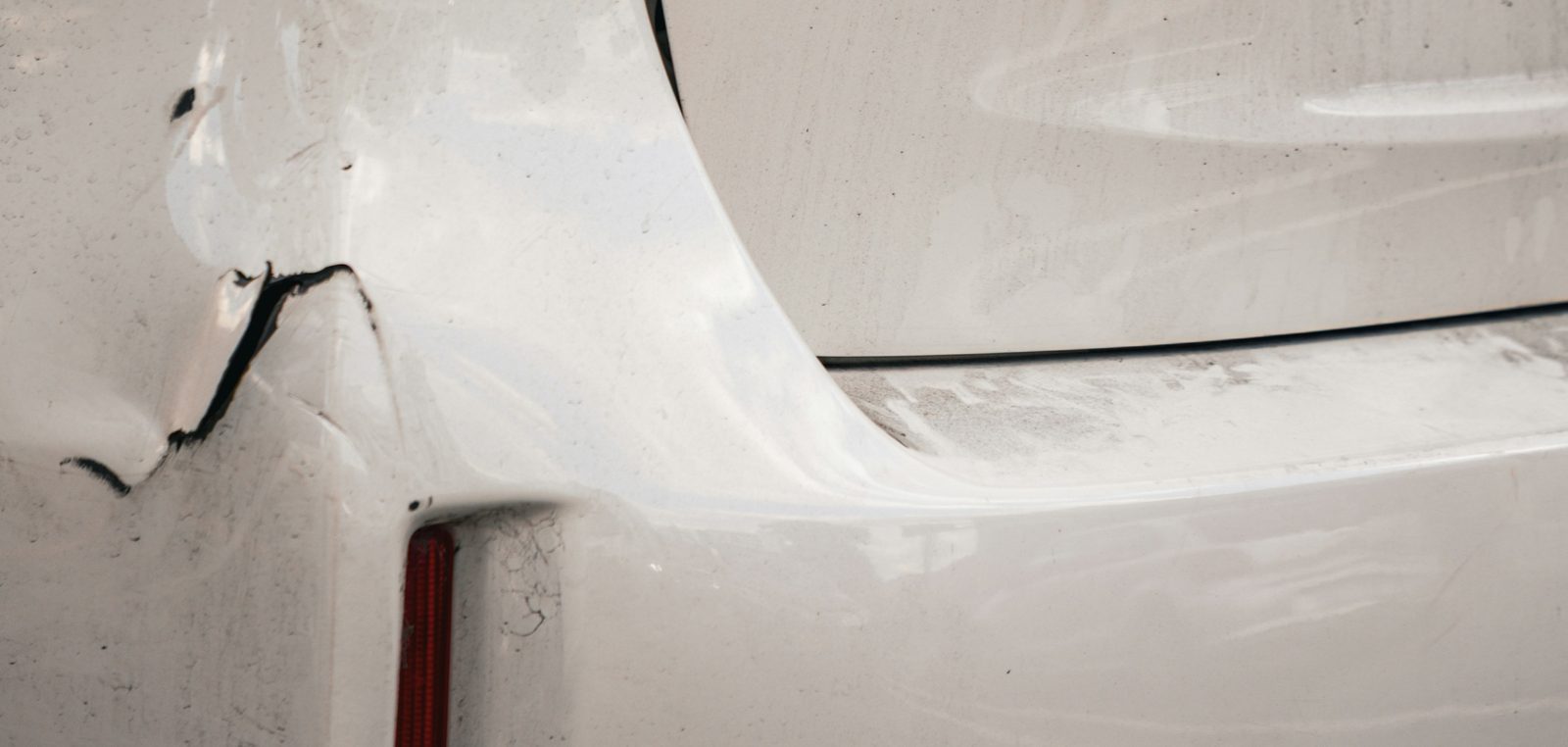 Eingedrückte Heckstoßstange eines weißen Autos nach einem Auffahrschaden