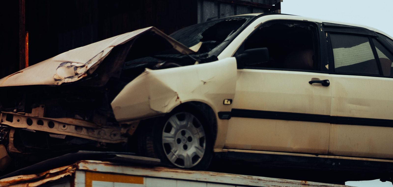 Beiges Auto mit vollständig eingedrückter Front nach einem Unfall