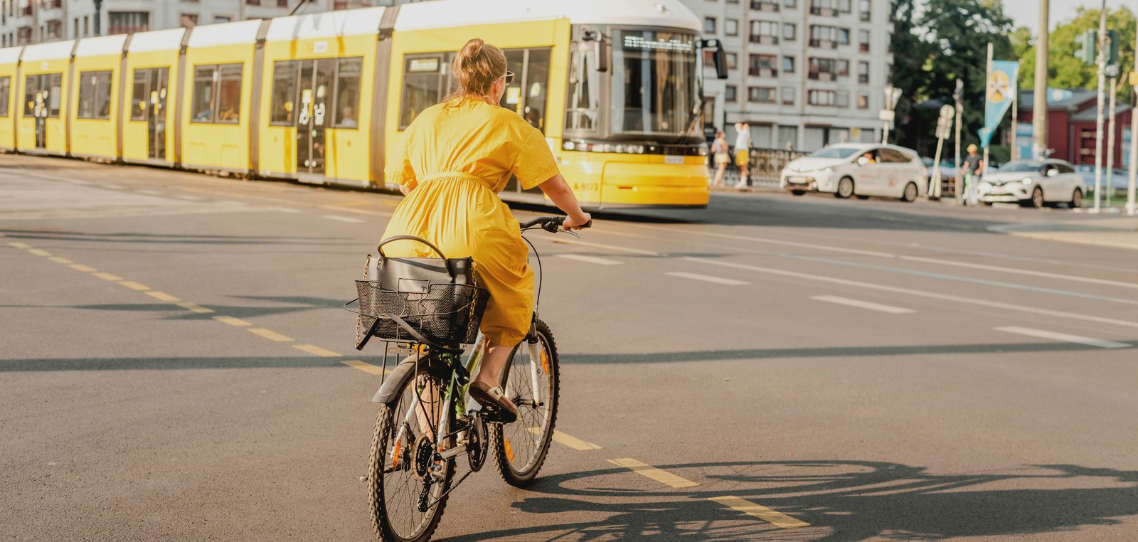 Frau fährt mit dem Fahrrad an einer gelben Straßenbahn vorbei
